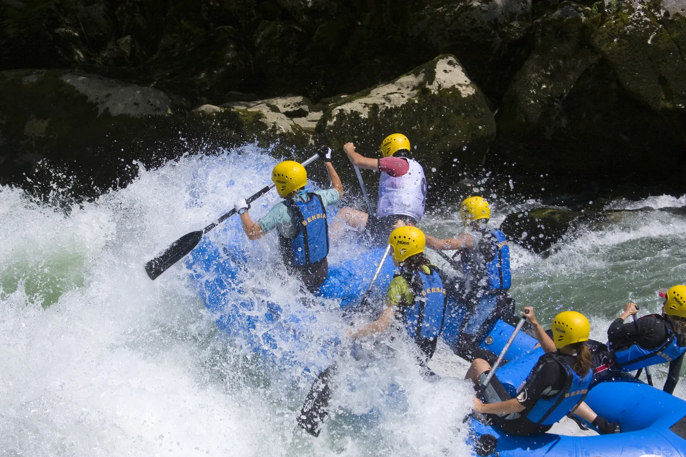 A whitewater rafting group powering through a rapid