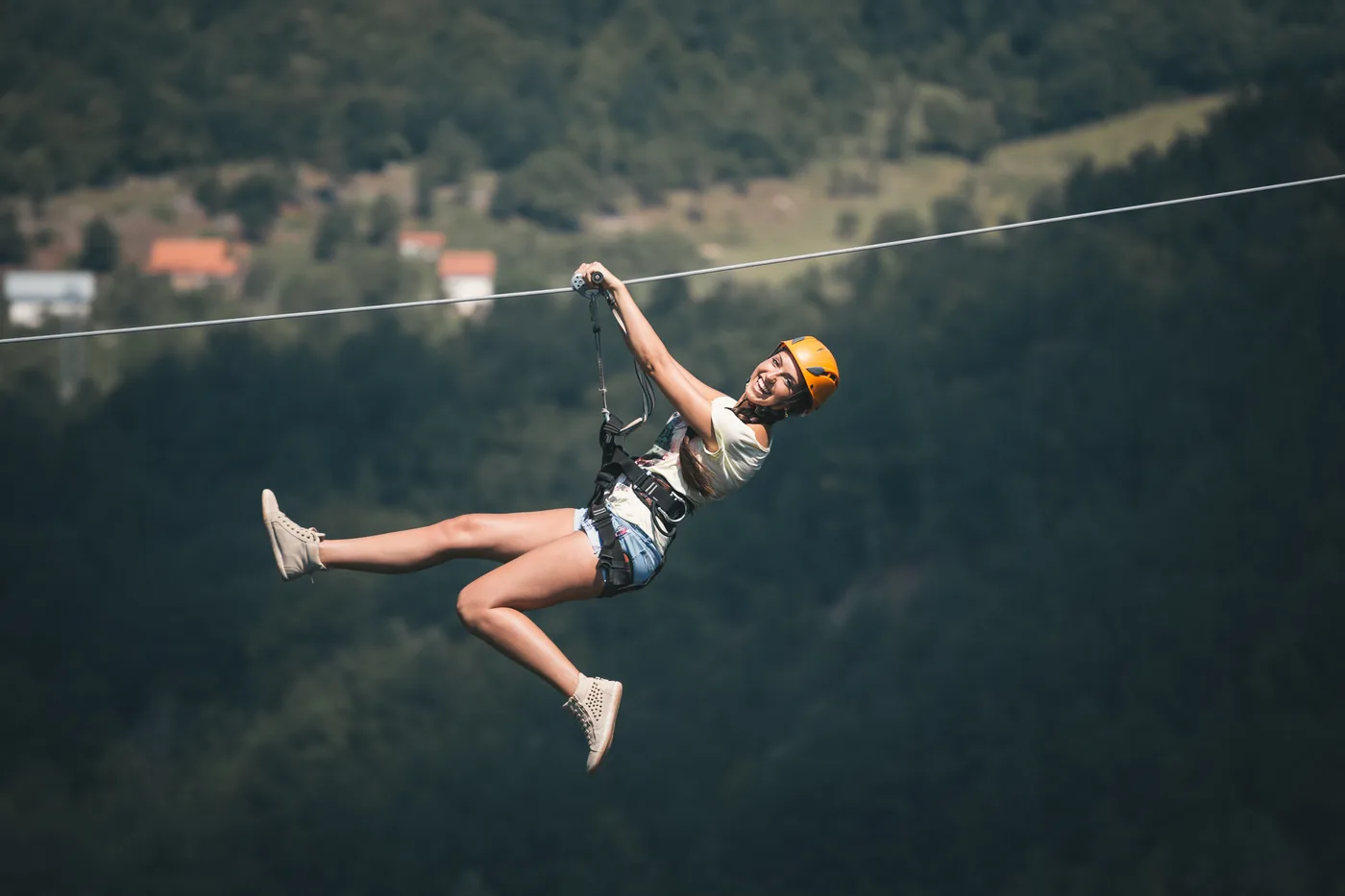 A guest riding a zip line across a mountain valley